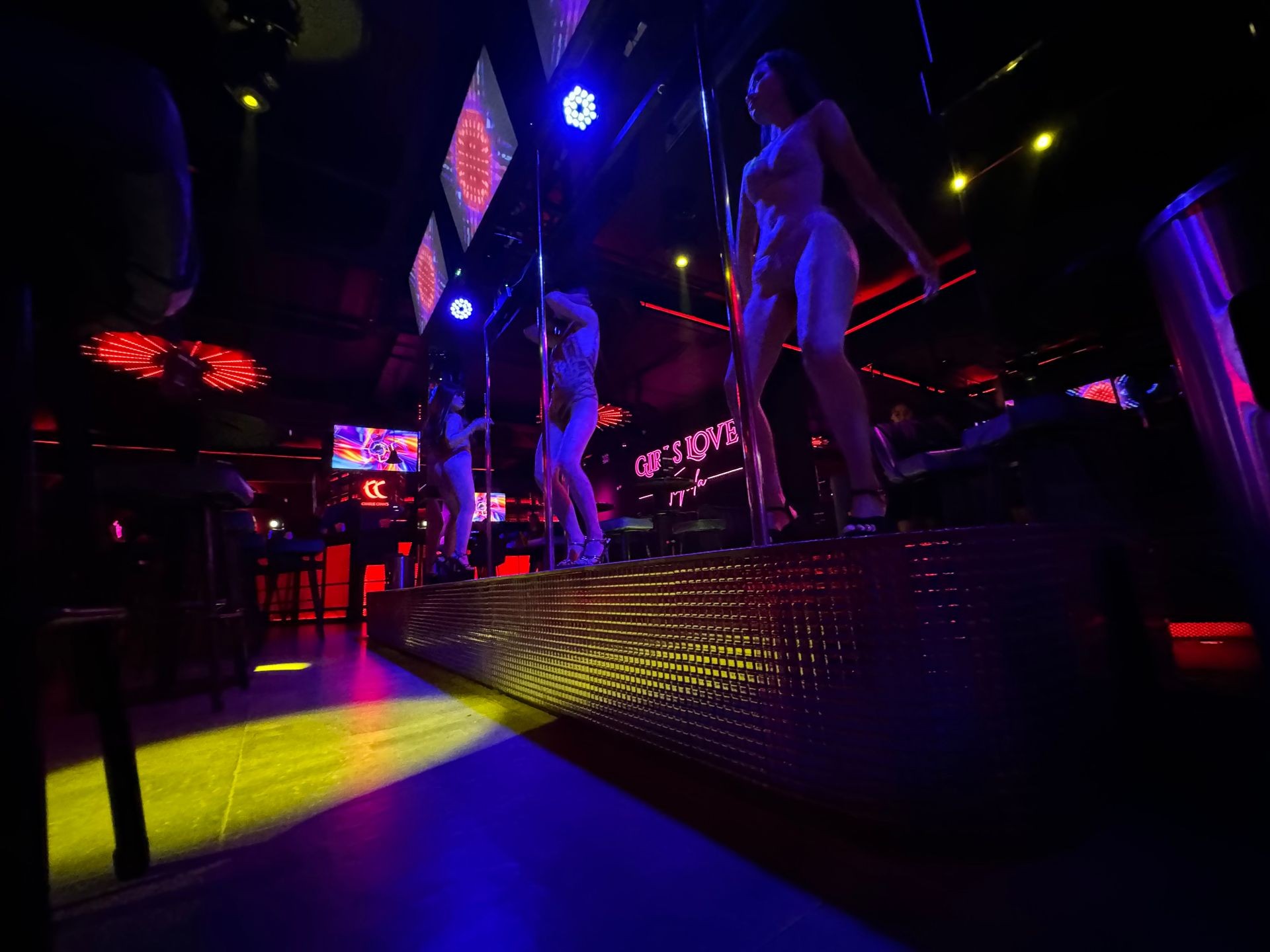 Dancers performing on a stage with colorful lighting in a nightclub setting.