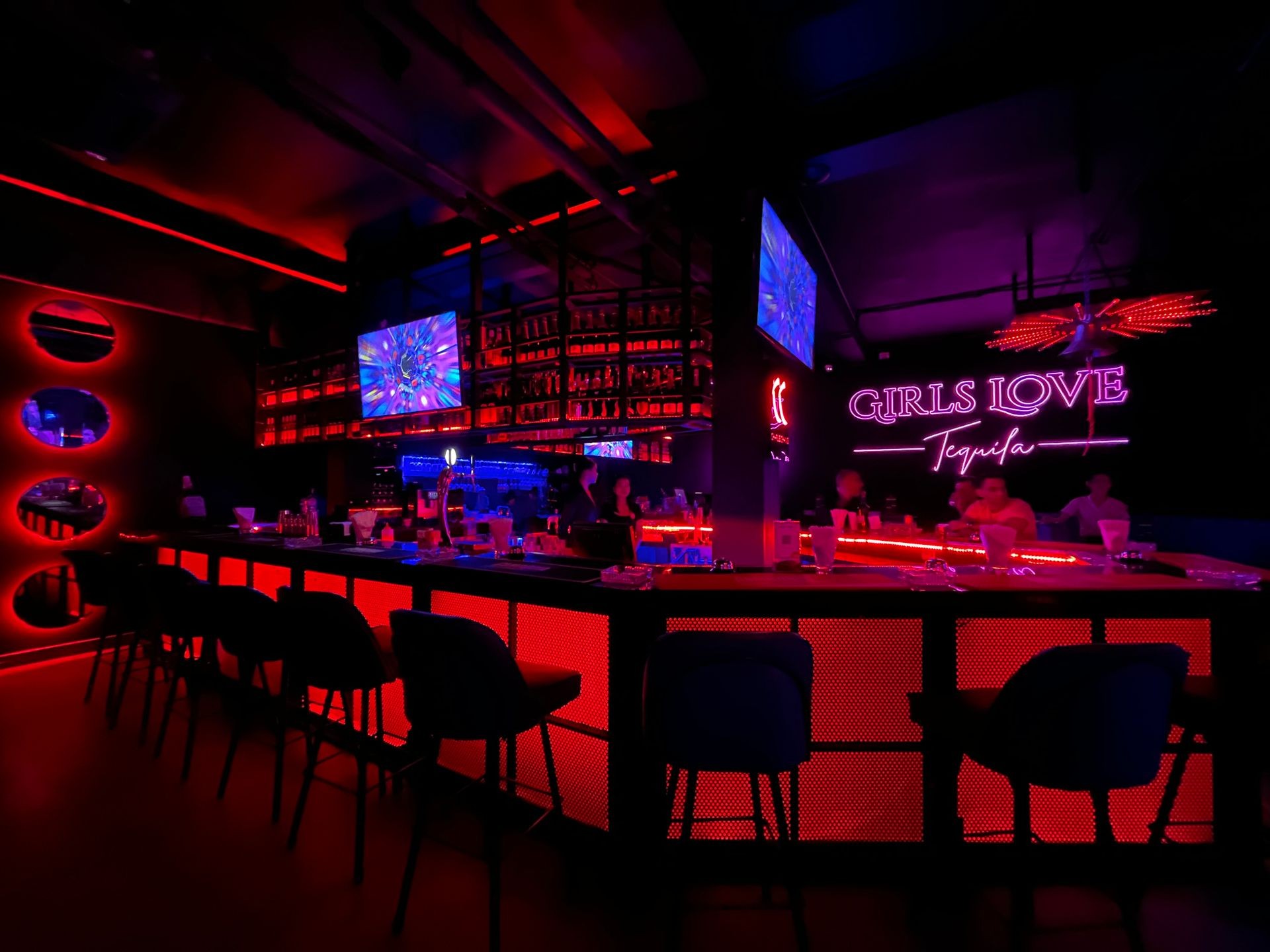 Dimly lit bar with neon lights and 'Girls Love Tequila' sign.