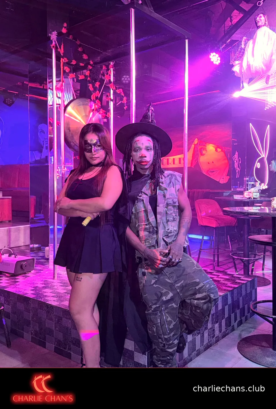 Two team members in Halloween costumes posing beside the stage