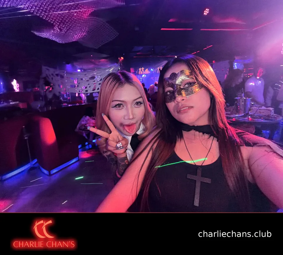 Two team members in Halloween costumes posing under the club lights
