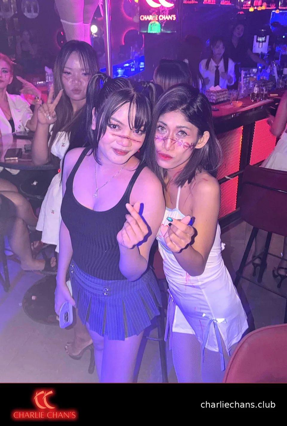 Two team members in Halloween makeup making finger-heart poses