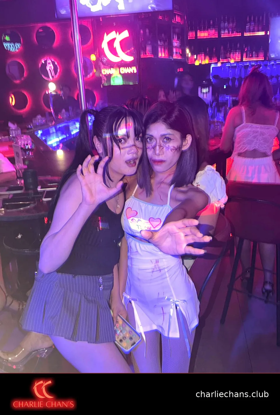 Two team members in Halloween makeup posing beside the illuminated bar