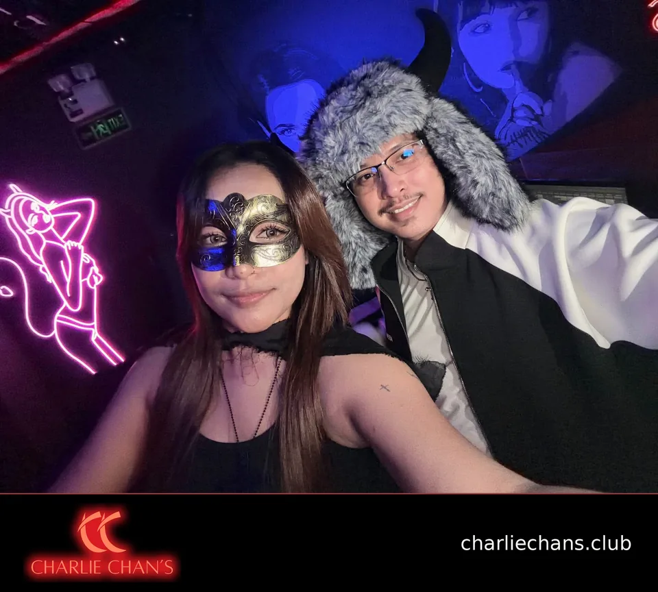 Two team members in Halloween costumes posing beneath the club lights